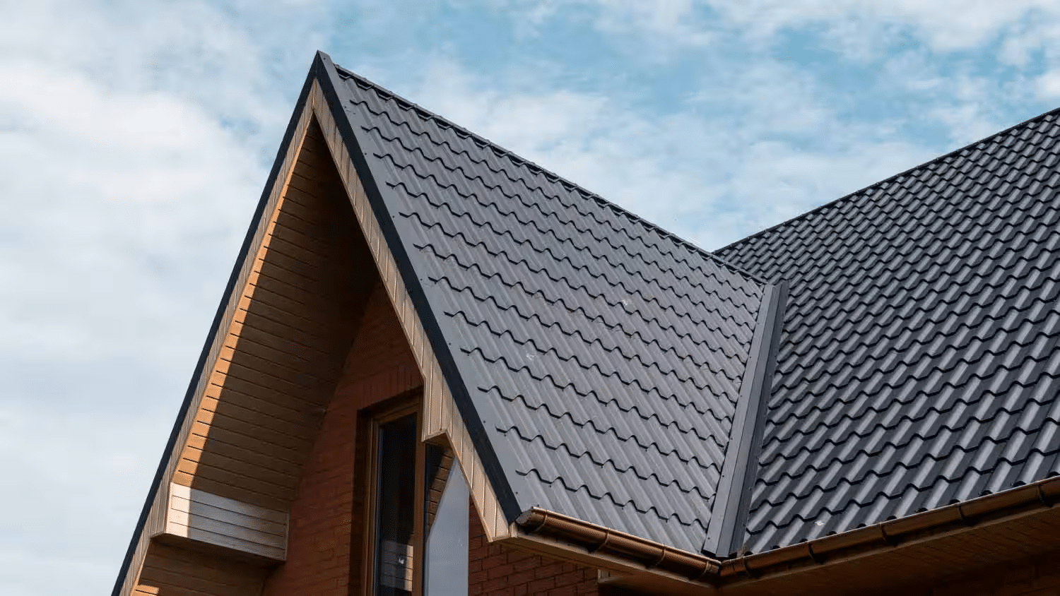Two professional roofing contractors install dark tiles during a high-quality roof installation.