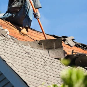 Worker fixing roof tiles providing emergency roof repair.